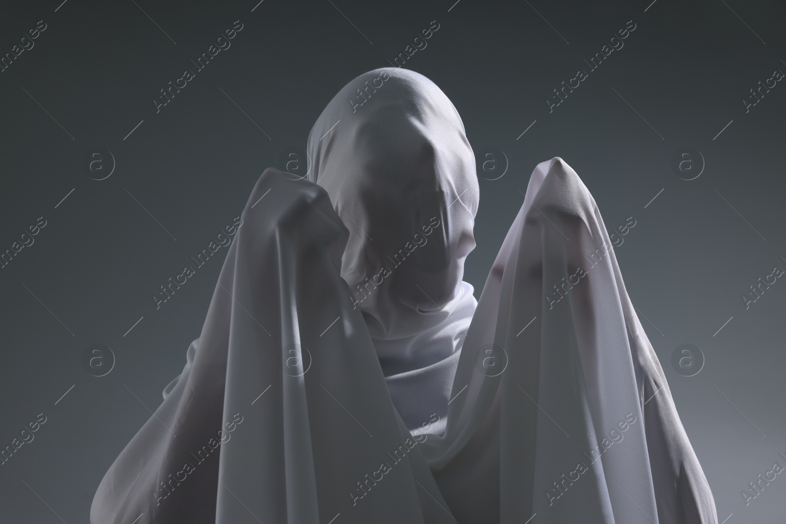 Creepy ghost. Man covered with white sheet on light grey background Photo of Creepy ghost. Man covered with white sheet on light grey background