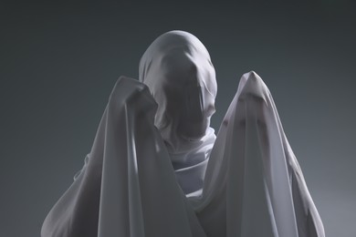 Photo of Creepy ghost. Man covered with white sheet on light grey background