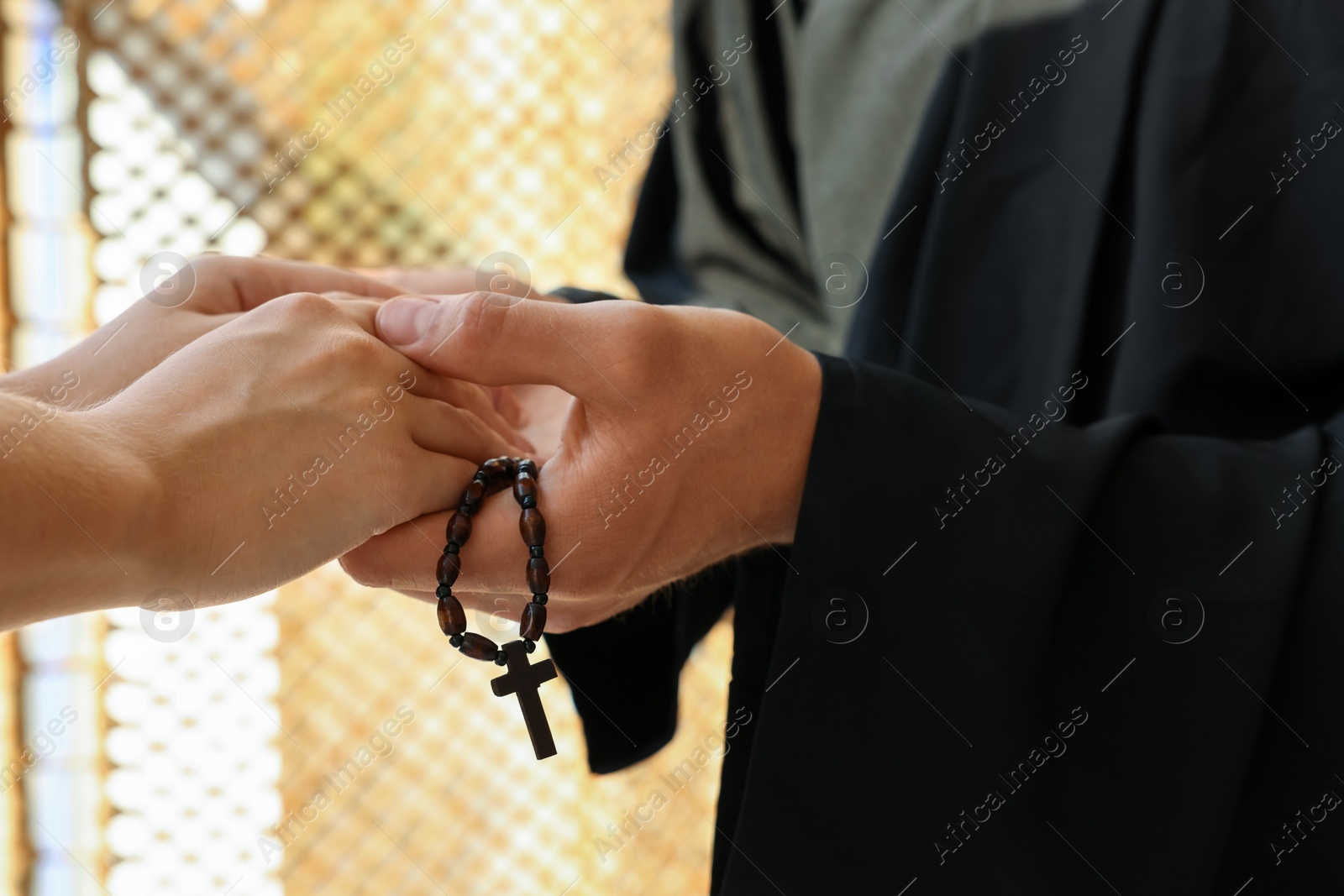 Photo of Priest and woman holding hands indoors, closeup