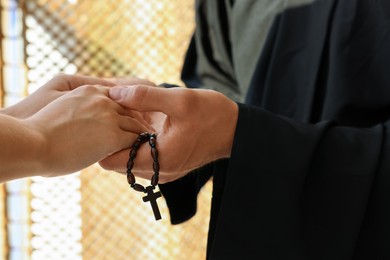 Photo of Priest and woman holding hands indoors, closeup