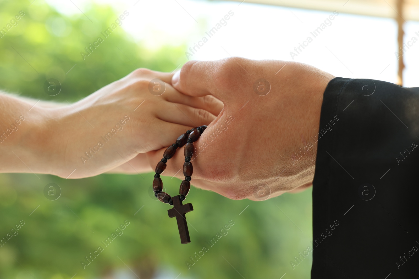 Photo of Priest and woman holding hands outdoors, closeup