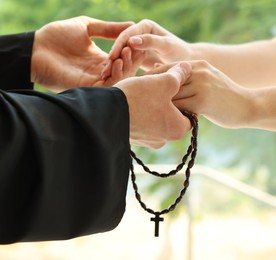 Photo of Priest and woman holding hands outdoors, closeup