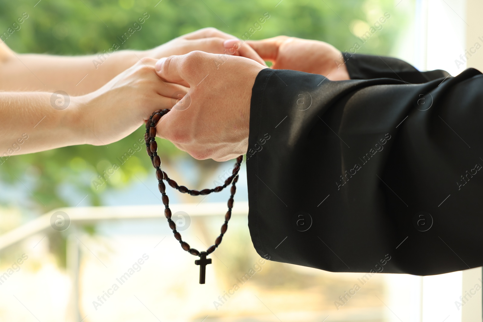 Photo of Priest and woman holding hands outdoors, closeup