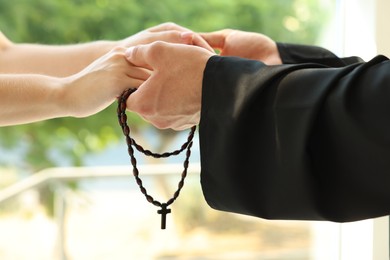 Photo of Priest and woman holding hands outdoors, closeup