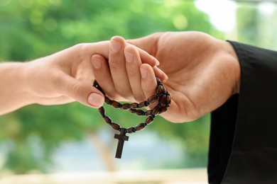 Photo of Priest and woman holding hands outdoors, closeup