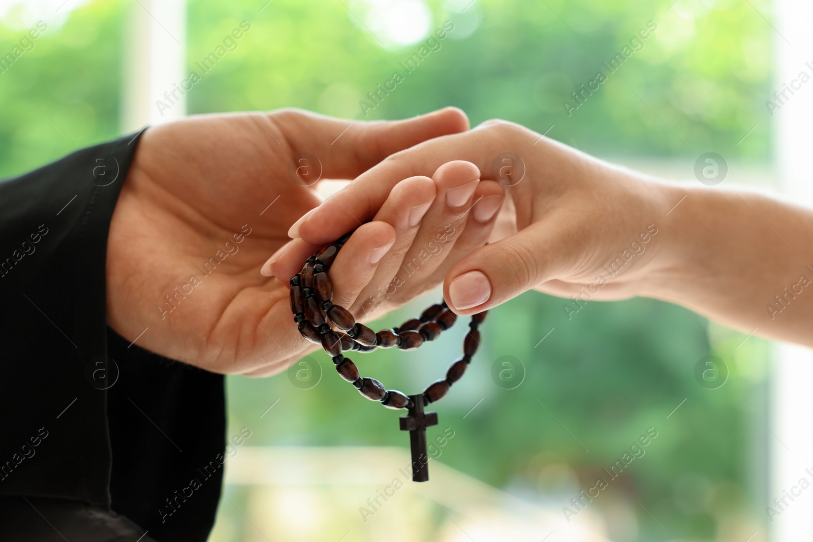 Photo of Priest and woman holding hands outdoors, closeup