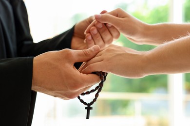 Photo of Priest and woman holding hands outdoors, closeup