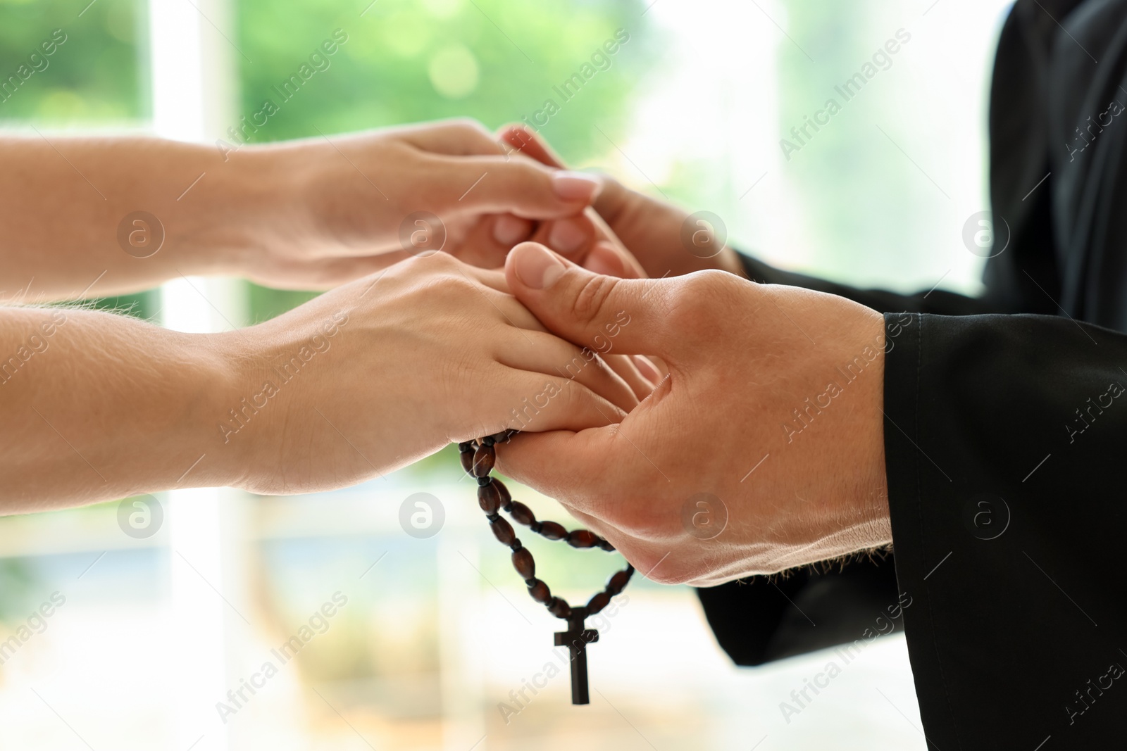 Photo of Priest and woman holding hands outdoors, closeup