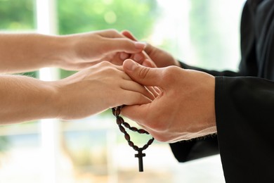 Photo of Priest and woman holding hands outdoors, closeup