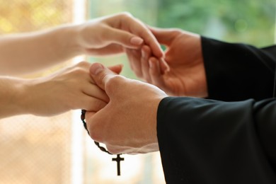 Photo of Priest and woman holding hands outdoors, closeup
