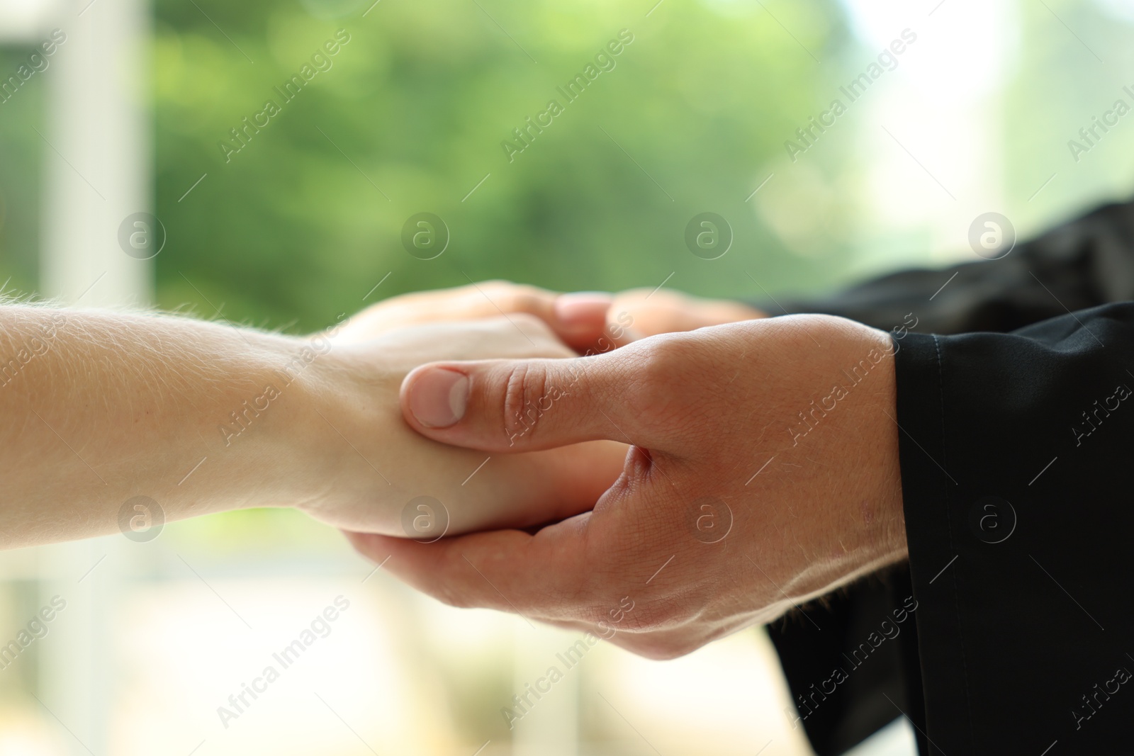 Photo of Priest and woman holding hands outdoors, closeup