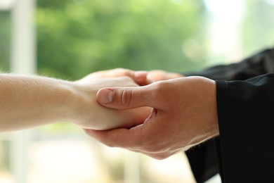 Photo of Priest and woman holding hands outdoors, closeup