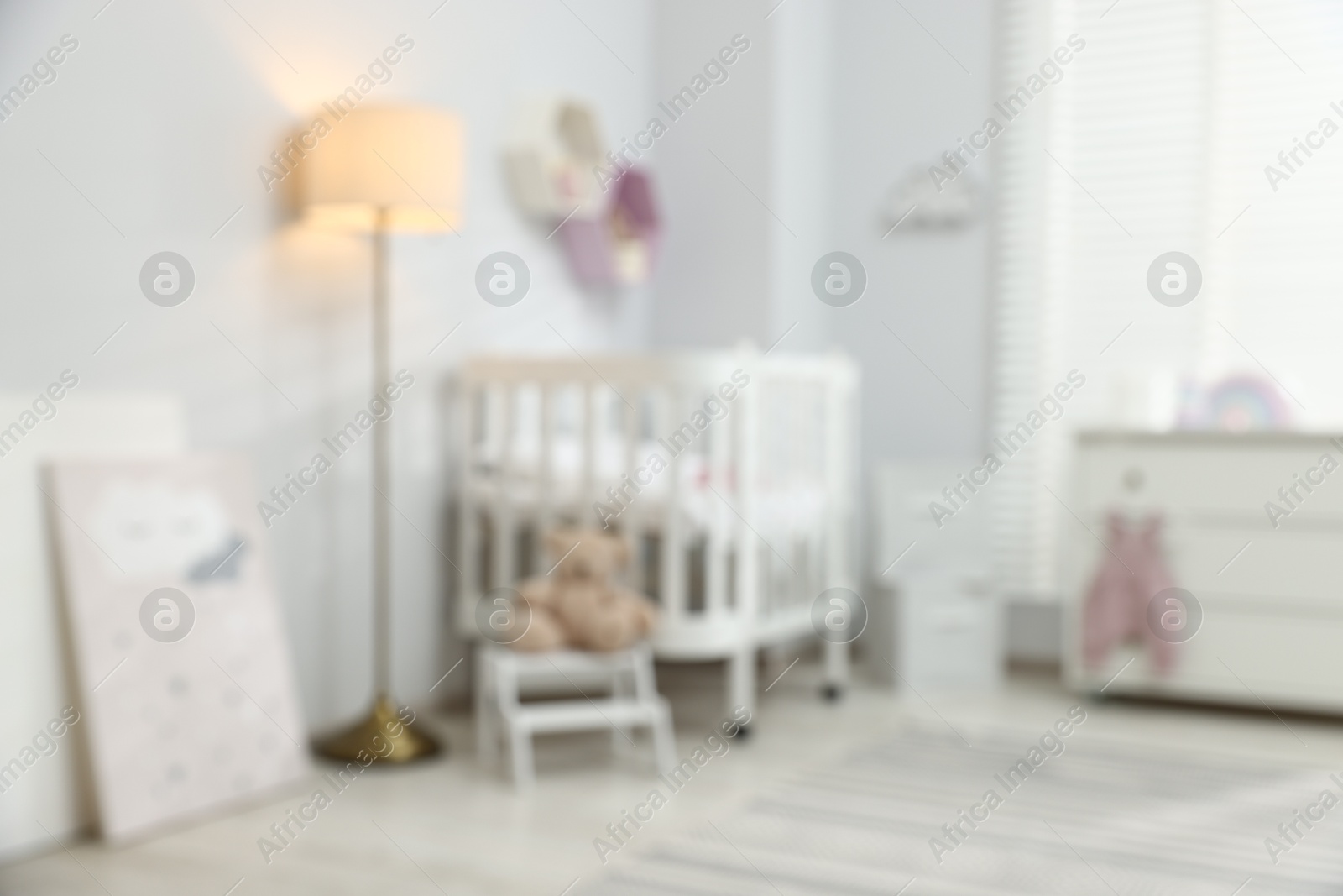 Baby room with comfortable crib and other furniture, blurred view. Interior design Photo of Baby room with comfortable crib and other furniture, blurred view. Interior design
