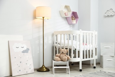 Photo of Cozy baby room interior with comfortable crib, toys and lamp