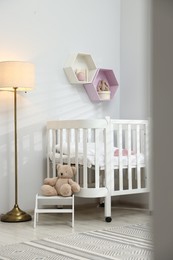 Photo of Cozy baby room interior with comfortable crib, toys and lamp