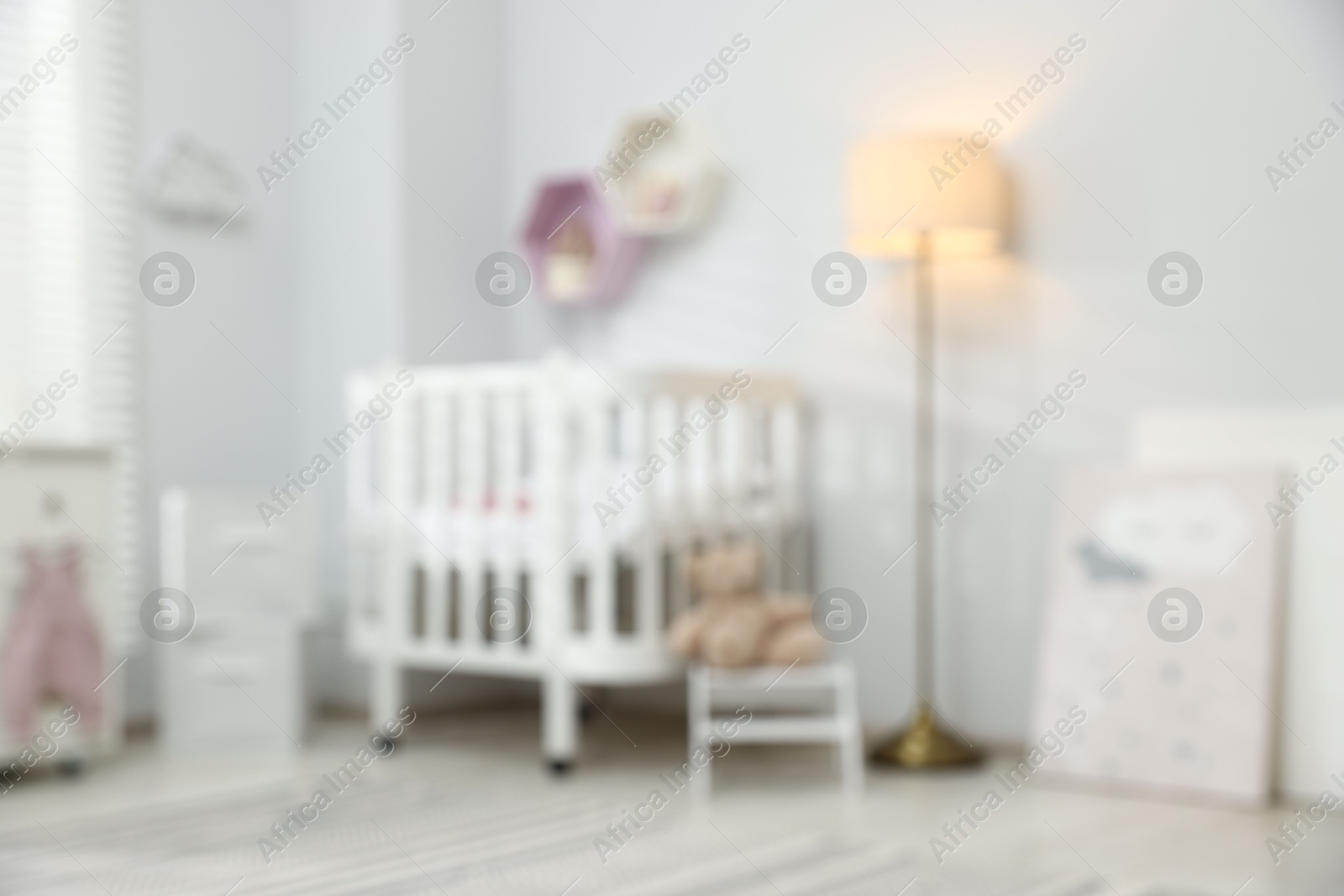 Cozy baby room with crib and decor elements, blurred view. Interior design Photo of Cozy baby room with crib and decor elements, blurred view. Interior design