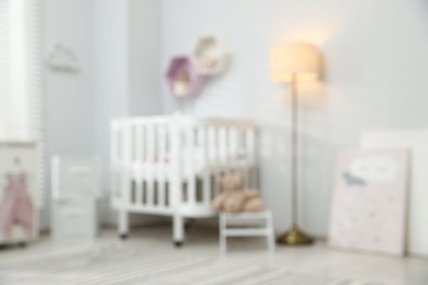 Photo of Cozy baby room with crib and decor elements, blurred view. Interior design