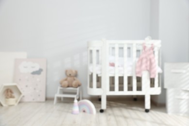 Photo of Baby room interior with comfortable crib and other furniture, blurred view