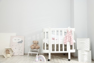Photo of Stylish baby room interior with comfortable crib and other furniture