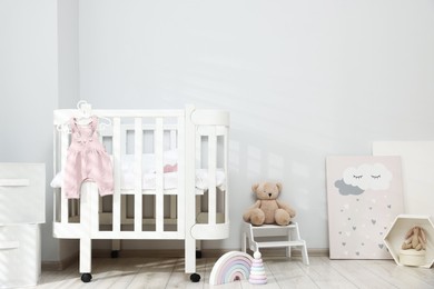 Photo of Stylish baby room interior with comfortable crib and other furniture