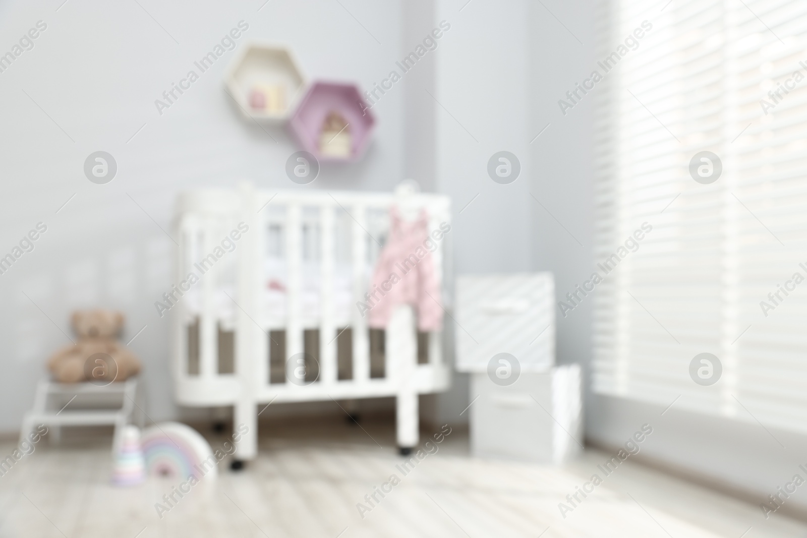 Baby room interior with comfortable crib and other furniture, blurred view Photo of Baby room interior with comfortable crib and other furniture, blurred view
