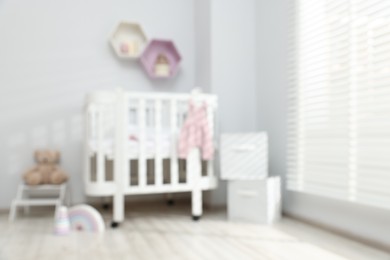 Photo of Baby room interior with comfortable crib and other furniture, blurred view