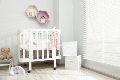 Photo of Stylish baby room interior with comfortable crib and other furniture