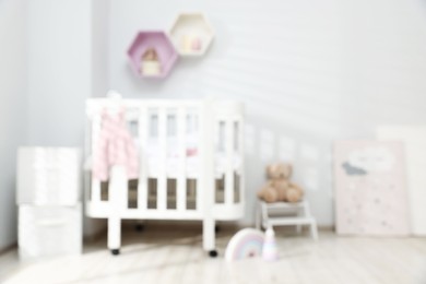 Photo of Baby room interior with comfortable crib and other furniture, blurred view