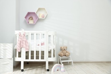 Photo of Stylish baby room interior with comfortable crib and other furniture
