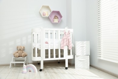 Photo of Stylish baby room interior with comfortable crib and other furniture