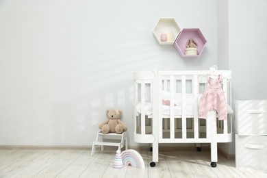 Photo of Stylish baby room interior with comfortable crib and other furniture