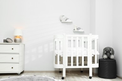 Photo of Stylish baby room interior with comfortable crib and other furniture