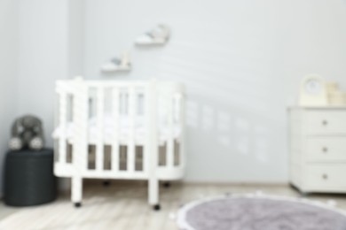 Photo of Baby room interior with comfortable crib and other furniture, blurred view