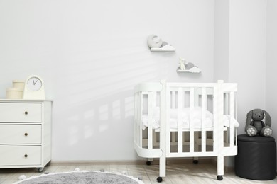 Photo of Stylish baby room interior with comfortable crib and other furniture