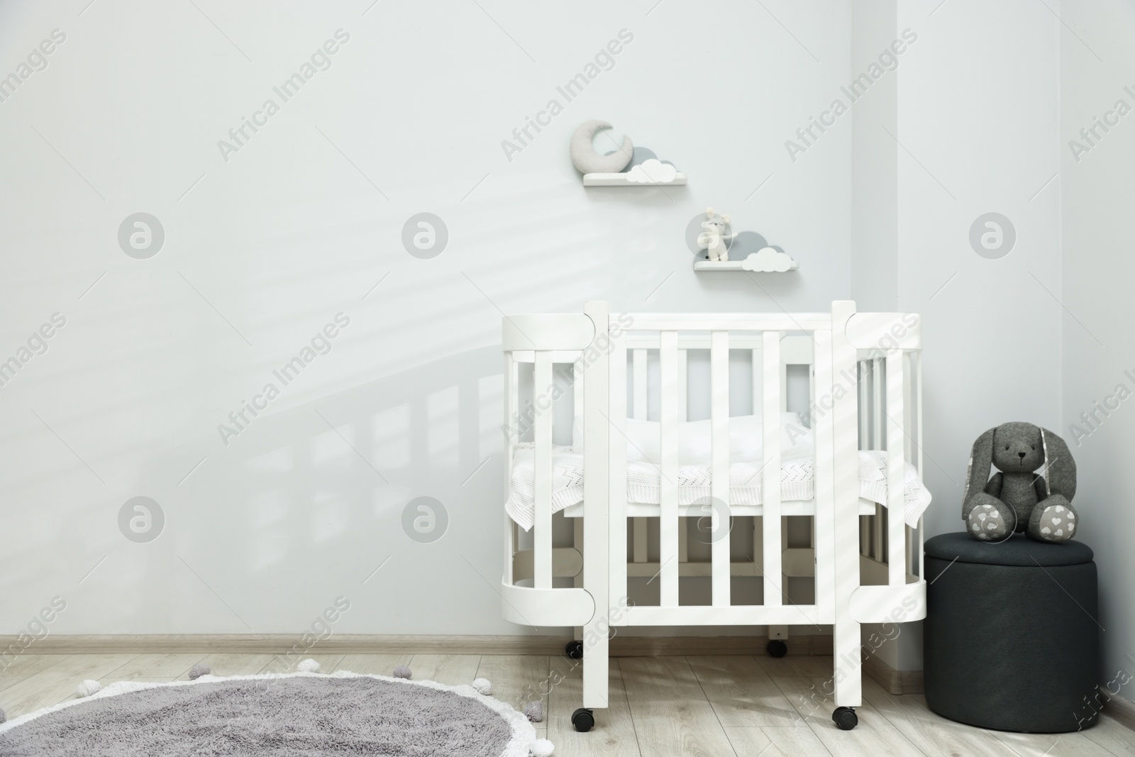 Stylish baby room interior with comfortable crib, pouf and toys. Space for text Photo of Stylish baby room interior with comfortable crib, pouf and toys. Space for text