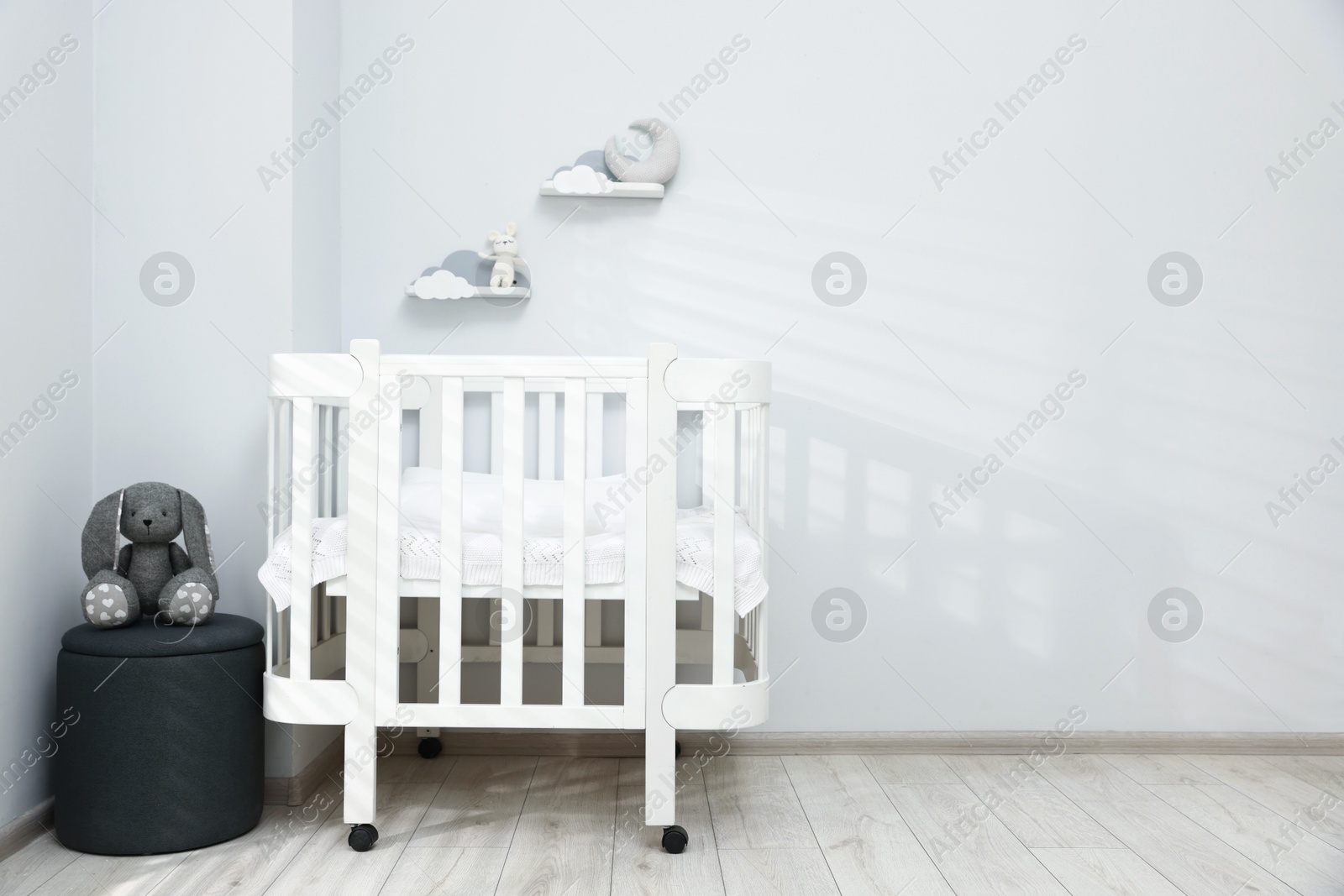 Stylish baby room interior with comfortable crib, pouf and toys. Space for text Photo of Stylish baby room interior with comfortable crib, pouf and toys. Space for text