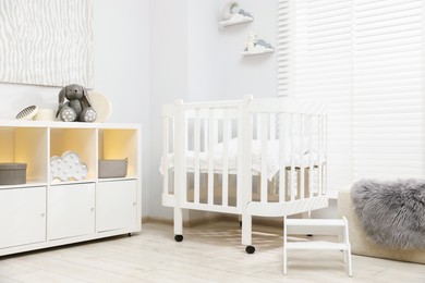 Photo of Beautiful baby room interior with stylish crib, other furniture and toys