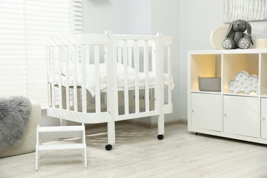 Photo of Beautiful baby room interior with stylish crib, other furniture and toys