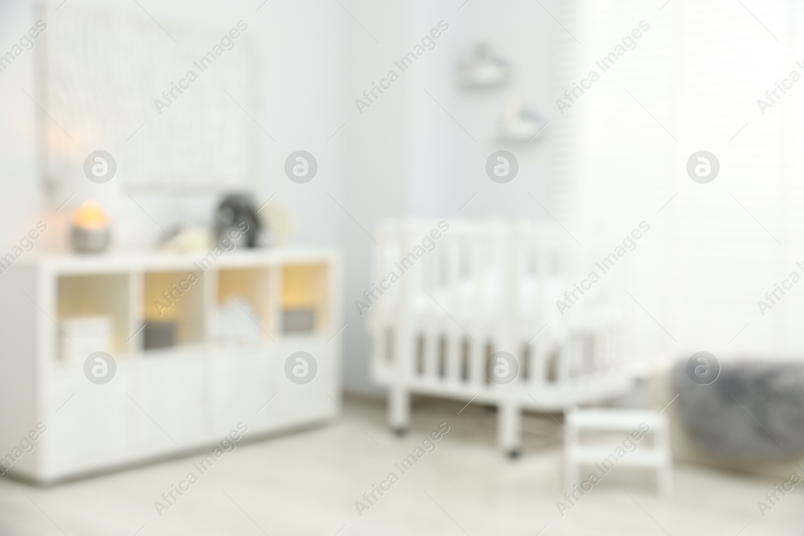 Baby room interior with stylish crib and other furniture, blurred view Photo of Baby room interior with stylish crib and other furniture, blurred view
