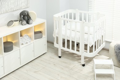 Photo of Beautiful baby room interior with stylish crib, other furniture and toys