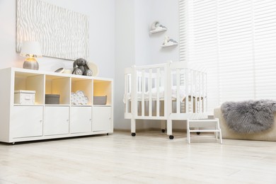 Photo of Beautiful baby room interior with stylish crib, other furniture and toys, low angle view