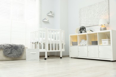 Photo of Beautiful baby room interior with stylish crib, other furniture and toys, low angle view