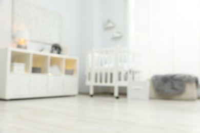 Photo of Blurred view of baby room interior with stylish crib and other furniture, low angle view
