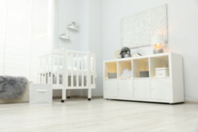 Photo of Blurred view of baby room interior with stylish crib and other furniture, low angle view