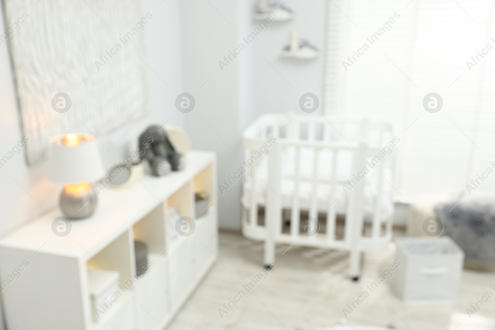 Beautiful baby room interior with stylish crib and other furniture, blurred view Photo of Beautiful baby room interior with stylish crib and other furniture, blurred view
