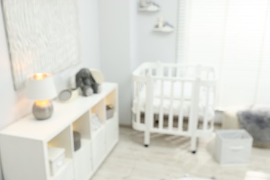 Photo of Beautiful baby room interior with stylish crib and other furniture, blurred view