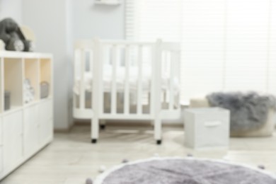 Photo of Baby room interior with stylish crib and other furniture, blurred view