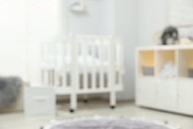Photo of Baby room interior with stylish crib and other furniture, blurred view