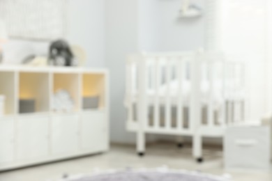 Photo of Baby room interior with stylish crib and other furniture, blurred view