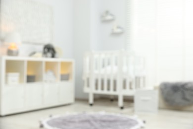 Photo of Baby room interior with stylish crib and other furniture, blurred view